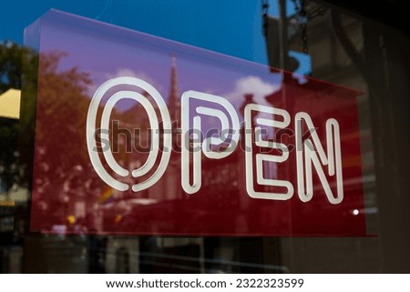 White neon open sign with a red background in a shop window