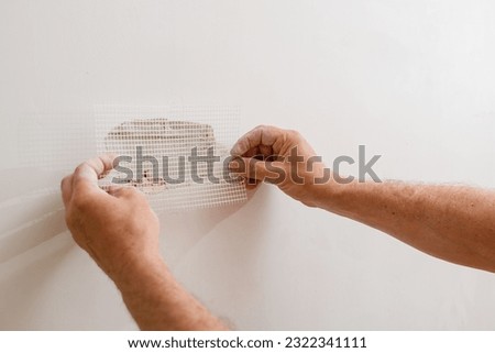 Repairing holes in drywall. A handyman is repairing a hole in the drywall in the wall. Royalty-Free Stock Photo #2322341111