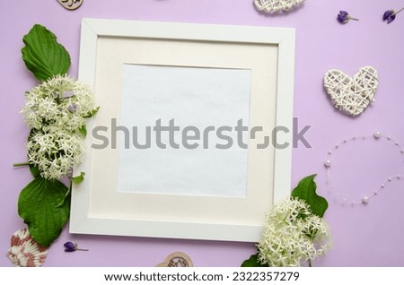 White frame with white wild flowers and leaves with decorative heart and pearls on a purple background. Space for text.
