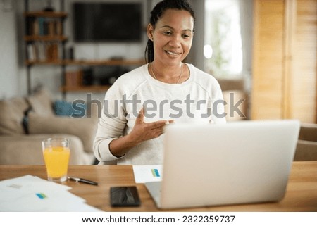 Happy African American woman having a video call over laptop at home.