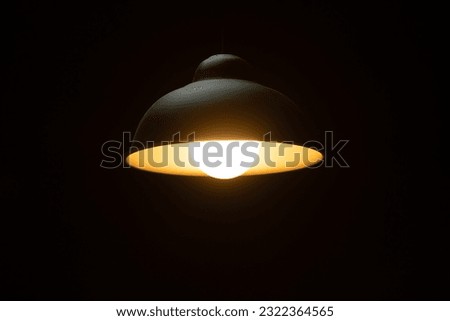 Warm orange LED lamp in the ceiling on a dark background in the center of the frame, bottom view.