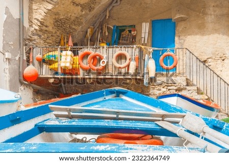 Blue dinghy and oars with defocused nautical background and door in rock wall.