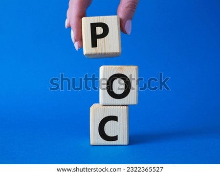 POC - Proof of Concept symbol. Wooden cubes with words POC. Businessman hand. Beautiful blue background. Business and POC concept. Copy space.