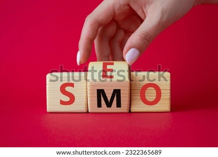 SEO vs SMO symbol. Businessman hand turns wooden cubes and changes the word SMO to SEO. Beautiful red background. SEO vs SMO and business concept. Copy space
