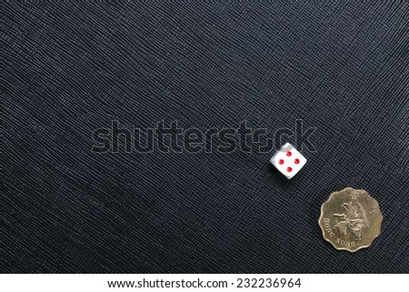 Hongkong dollar coin and dice put on the black color leather surface as a background represent the finance and gambling.