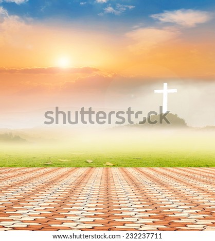 Stone paving and the white cross on sunset background.