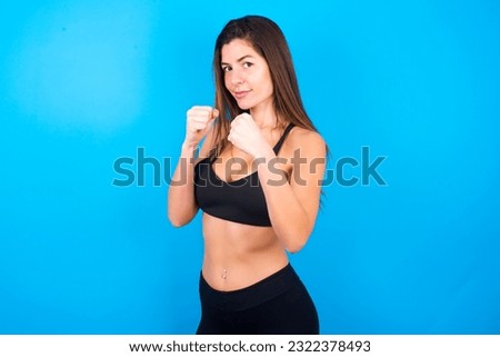 Portrait of attractive Young beautiful brunette woman wearing sportswear holding hands in front of him in boxing position going to fight.