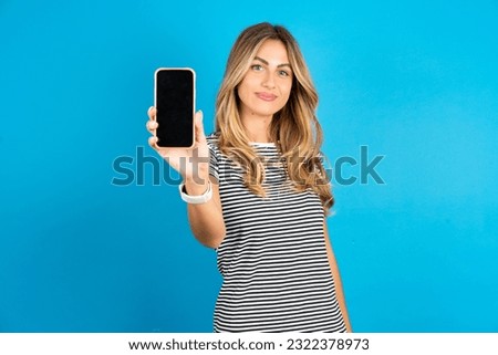 Smiling Young beautiful woman wearing striped t-shirt Mock up copy space. Hold mobile phone with blank empty screen