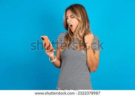Angry Young beautiful woman wearing striped t-shirt screaming on the phone, having an argument with an employee. Troubles at work.
