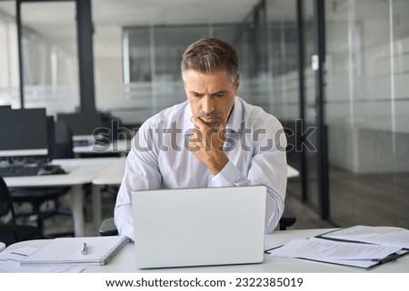 Serious busy mature professional business man company ceo executive manager investor looking at laptop pc computer sitting in office thinking of corporate management plan and financial strategy risks. Royalty-Free Stock Photo #2322385019
