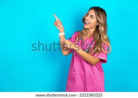 young beautiful doctor woman smile excited directing fingers look empty space
