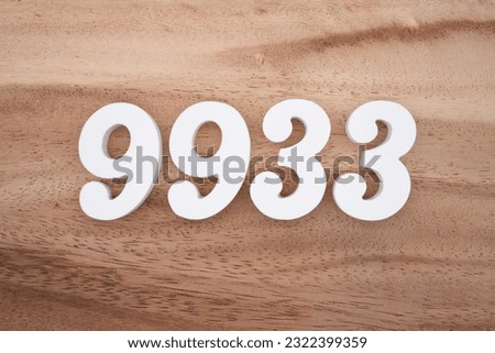 White number 9933 on a brown and light brown wooden background.