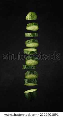fresh sliced cucumber flying vertically on a soft dark background with a spot of light.  moody art photo
