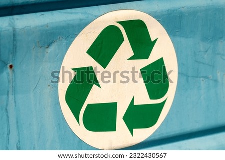Recycle sign on a blue painted metal dumpster