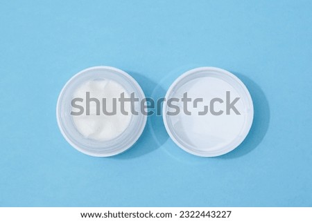 Beauty product photo of a white face cream on a blue background