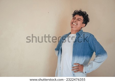 Young curly man wear denim clothes with painful face. The photo is suitable to use for man expression advertising and fashion lifestyle.