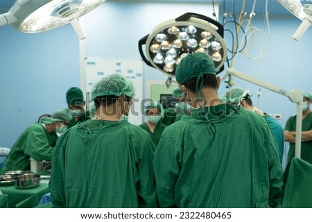 Medical team of surgeons in hospital working surgical intervention.Surgery operating room with electrocautery equipment for breast cosmetic.Surgeon gloved hands hold the instrument