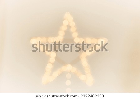 Yellow glowing light in the shape of a star. A bright star highlighted by a glow outline on a light background with space to copy. High quality photo