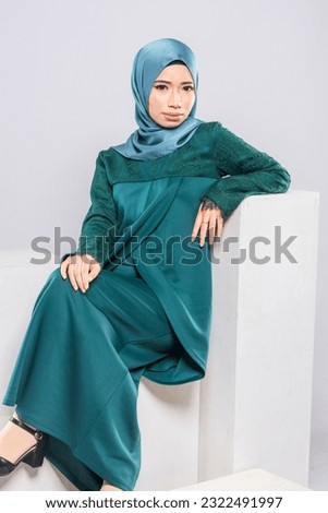 Young smiling confident asian muslim woman in hijab over isolated over background studio. Casual hijab fashion.