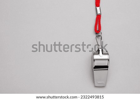 One metal whistle with red cord on light grey background, top view. Space for text Royalty-Free Stock Photo #2322493815