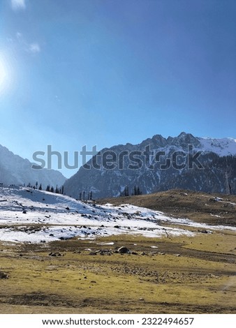 Blue sky and rain on green mountains, snow in front and green land