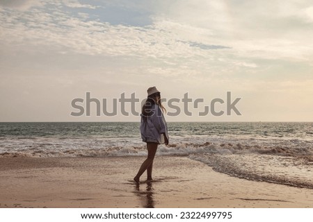 Full length of young woman walking on tropical sea beach at waves background. Cute lady in beachwear relaxing and enjoying, posing in tropics coast. Travel vacation holiday concept. Copy ad text space