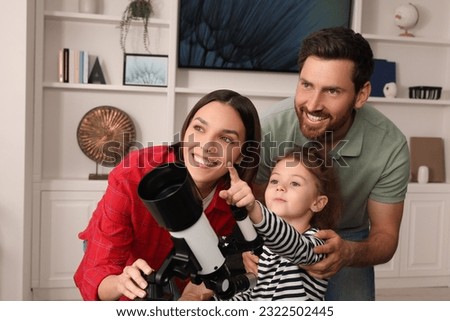 Happy family using telescope to look at stars in room