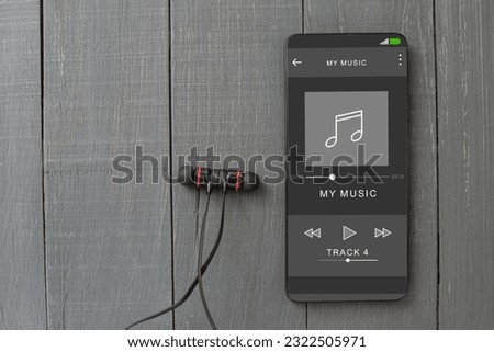Wired headphones and a phone on the table. Mobile phone and headphones, music is playing on the player. Close-up. Player on screen, copy space Royalty-Free Stock Photo #2322505971