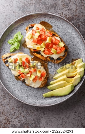 Grilled California Avocado Chicken topped with a mozzarella cheese and avocados, tomatoes, and basil closeup on the plate. Vertical top view from above
