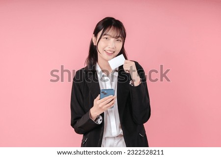 Photo of business young woman posing isolated over pink background using mobile phone holding debit or credit card.