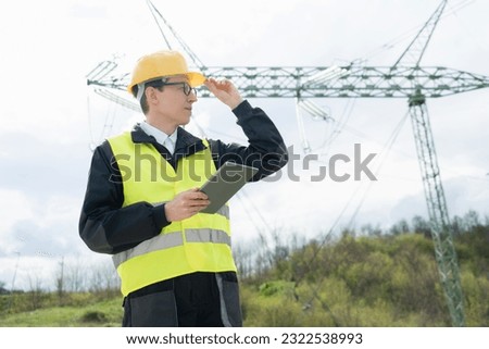 Engineer with digital tablet on a background of power line tower	