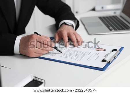 Human resources manager reading applicant's resume at table in office, closeup