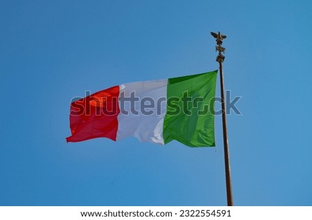 Italy's flag in red, white and green against a blue sky