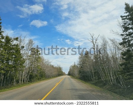 An open road under a cloudy sky running through a rural area.