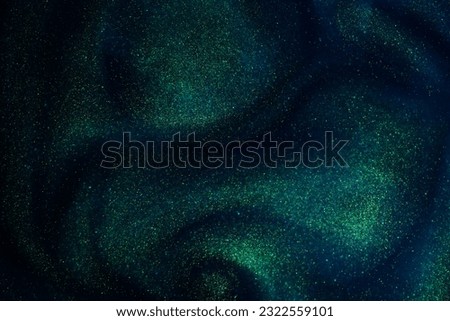 Abstract sparkling galaxy background. Golden glitter particles on a dark blue background with green hues. Golden dust particles magical stains and flows.  Royalty-Free Stock Photo #2322559101