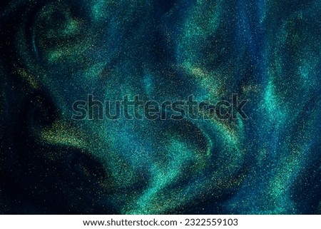 Various stains and overflows of gold particles in blue fluid with green tints. Golden particles dust and smooth defocused background. Liquid iridescent shiny backdrop with depth of field. Royalty-Free Stock Photo #2322559103