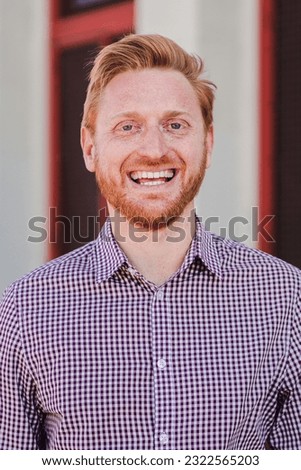 Vertical individual portrait of a formal joyful redhead formal guy standing outdoors smiling and looking at camera. Front view of positive young adult employee man laughing with friendly expression Royalty-Free Stock Photo #2322565203
