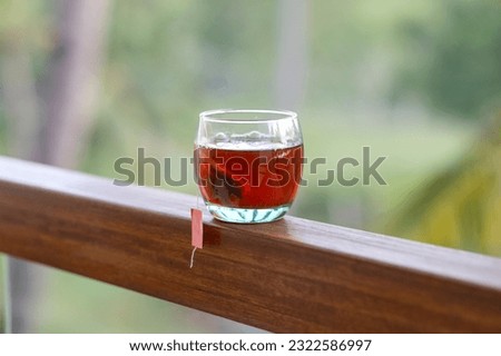 Tea bag in cup.  A cup of tea on the balcony railing in the heat.  Cup of tea in summer with garden background.