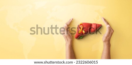 Hand hold liver organ with red yellow awareness ribbon on yellow background for banner of World Hepatitis day on July 28th Royalty-Free Stock Photo #2322606015