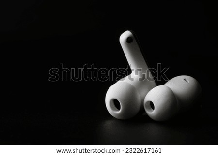A pair of white wireless tws headphones on a dark background. Modern technologies of the music industry. Photo. Copy space. Macro. Selective focus. Close-up