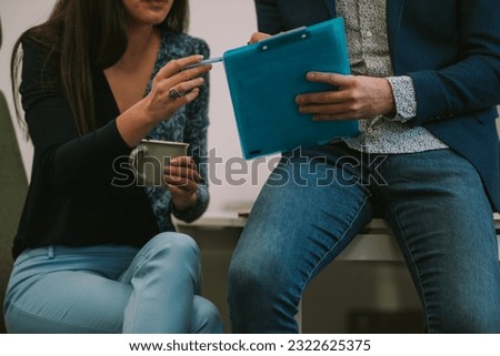 Close up of business woman pointing with her pen at the documents while sitting with her colleague at the office