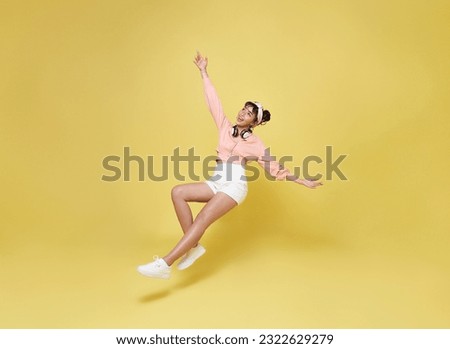 Happy smiling asian girl relaxing floating in mid-air isolated on yellow background. Royalty-Free Stock Photo #2322629279