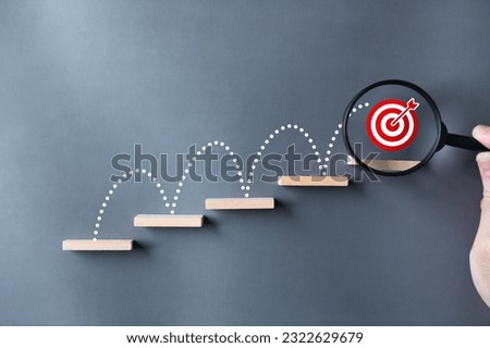 Unlock potential of business success stairs dart and dartboard targets magnifying glass with hand on gray background. Explore opportunities growth embrace steps to achieve ambitions and goal concept. Royalty-Free Stock Photo #2322629679