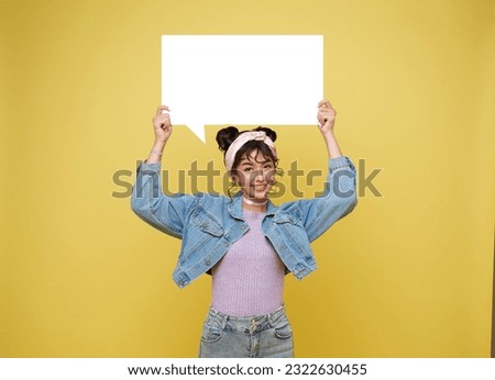 Happy smile Asian teen woman holding empty speech bubble isolated on yellow background.