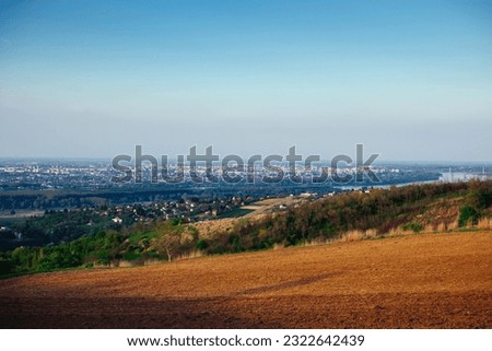 Panoramic view of the city of Novi Sad in Serbia from the top of Mount Fruska. View of the forest, fields, suburbs, city, the Danube River and bridges in spring sunny day.