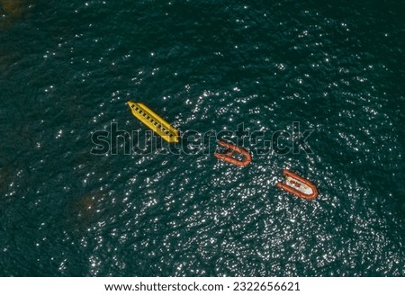 Aerial drone photography of a Banana Water Ride: A banana and two inflatable motorized rides, waiting to be used for fun.