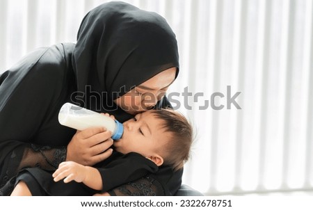 Muslim mother wearing traditional black dress and headscarf, carrying little boy, smiling with happiness, warm, praying, reading scripture, taking baby sleep, feeding milk. Family, Religious Concept