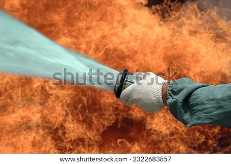 firefighting - fireman throwing water with a hose against a background of flames
