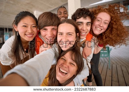Smiling group multi-ethnic students posing for selfie mobile phone gathered on college campus. Happy young friends and classmates hugging together for photo. Generation z people and back to school.