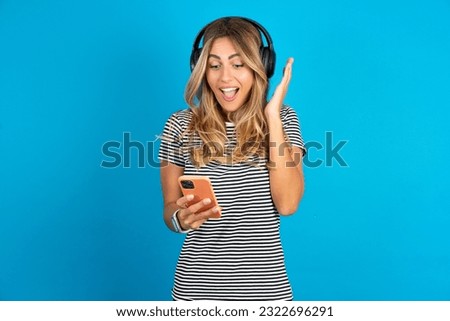 Young beautiful woman wearing striped t-shirt  holding in hands cell reading browsing news